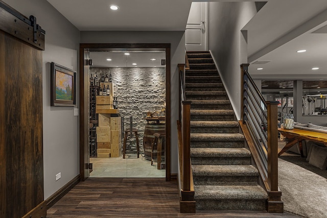 stairway with a barn door and hardwood / wood-style floors