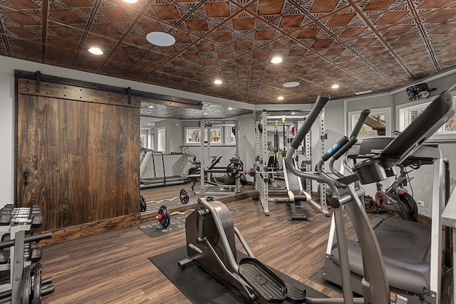 exercise room with hardwood / wood-style floors and a barn door