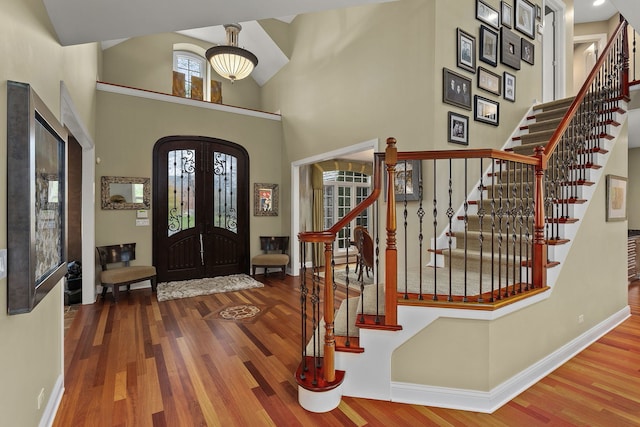 entrance foyer featuring hardwood / wood-style floors, high vaulted ceiling, and french doors