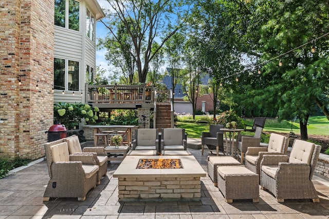 view of patio / terrace featuring a wooden deck and an outdoor living space with a fire pit