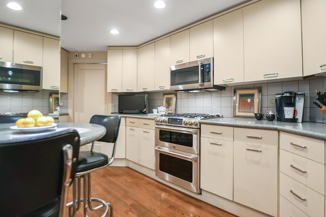 kitchen with decorative backsplash, light hardwood / wood-style floors, and appliances with stainless steel finishes