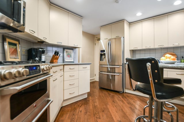 kitchen featuring hardwood / wood-style flooring, stainless steel appliances, and decorative backsplash