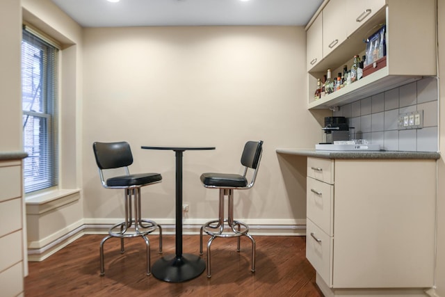 bar with dark wood-type flooring, white cabinetry, and decorative backsplash