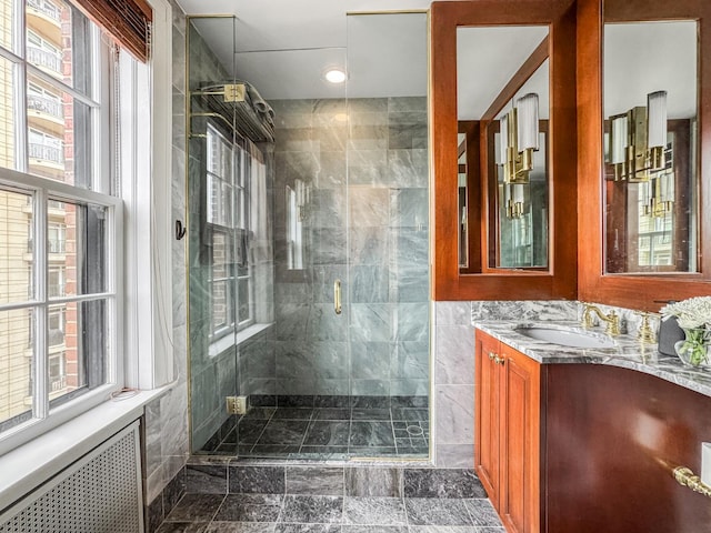 bathroom featuring vanity, radiator heating unit, tile walls, and walk in shower