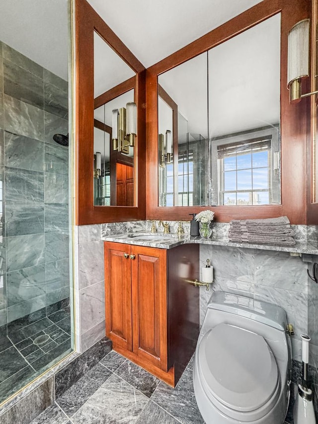 bathroom with tile walls, vanity, a shower with shower door, and toilet