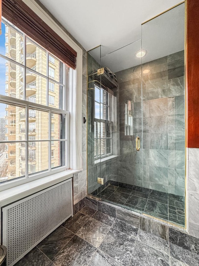 bathroom featuring a shower with door and radiator