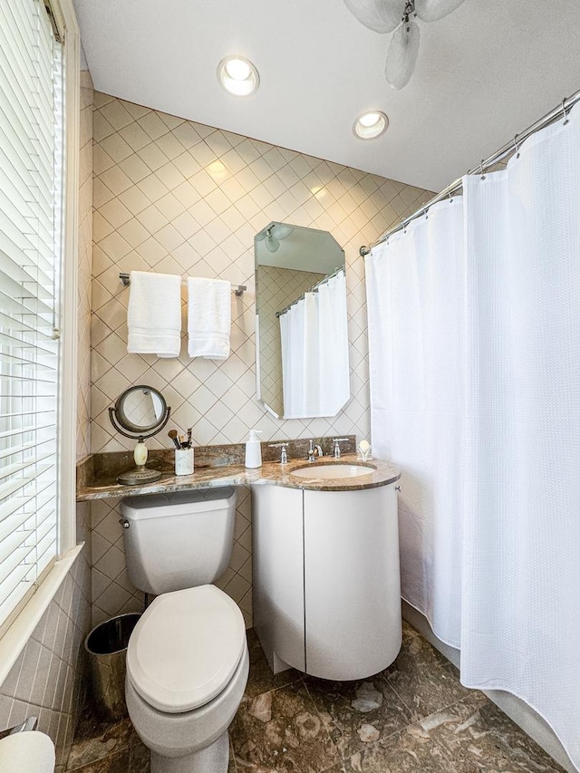 bathroom with vanity, toilet, and tile walls