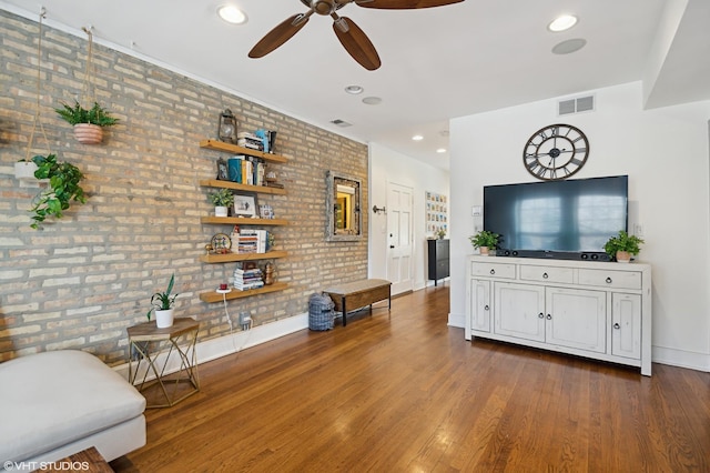 living room featuring dark hardwood / wood-style floors, ceiling fan, and brick wall