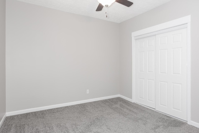 unfurnished bedroom with ceiling fan, a closet, carpet floors, and a textured ceiling