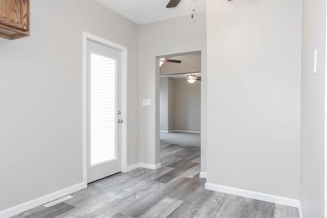 foyer entrance with ceiling fan and light wood-type flooring