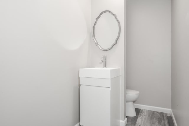 bathroom with vanity, toilet, and hardwood / wood-style floors