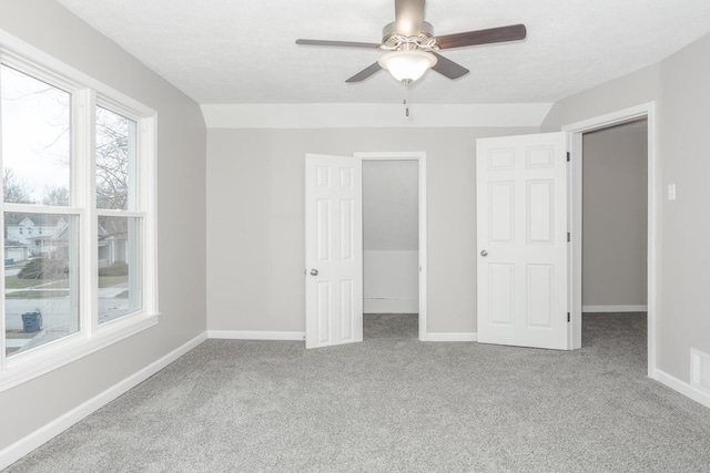 unfurnished bedroom with ceiling fan, a spacious closet, and light carpet