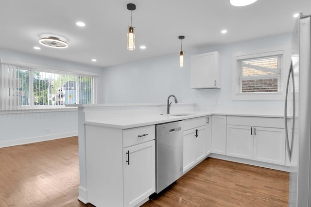 kitchen with white cabinets, kitchen peninsula, sink, and appliances with stainless steel finishes