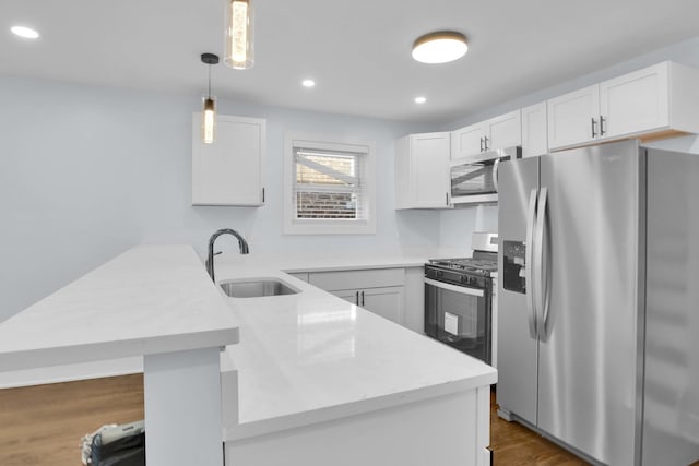 kitchen featuring kitchen peninsula, appliances with stainless steel finishes, sink, pendant lighting, and white cabinetry