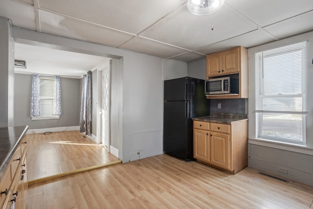 kitchen featuring a wealth of natural light, light hardwood / wood-style floors, and black fridge