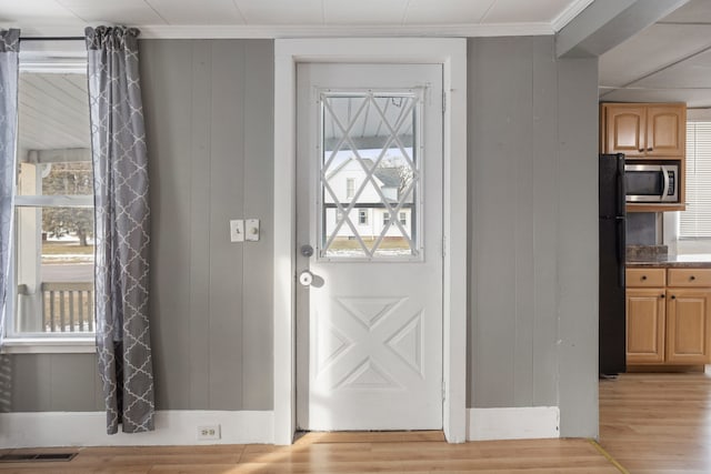 entryway featuring light hardwood / wood-style floors, wood walls, and crown molding