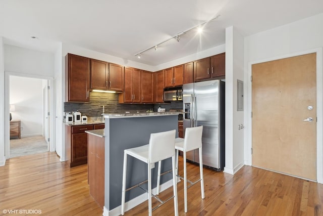 kitchen featuring a kitchen bar, stainless steel fridge, track lighting, light hardwood / wood-style flooring, and a kitchen island