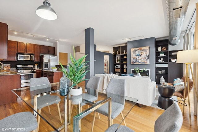 dining space with track lighting and light hardwood / wood-style flooring