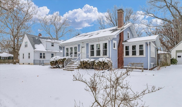 snow covered rear of property with an outbuilding and a garage