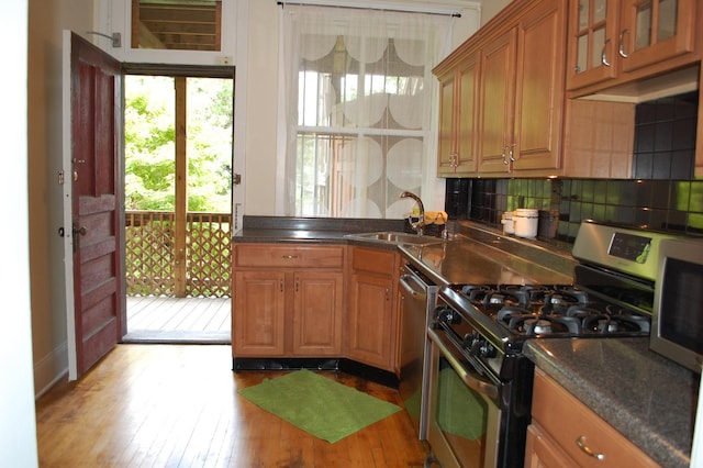 kitchen featuring decorative backsplash, sink, stainless steel appliances, and light hardwood / wood-style flooring