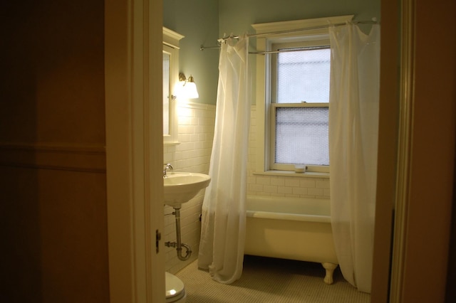 bathroom featuring toilet, tile walls, and shower / tub combo