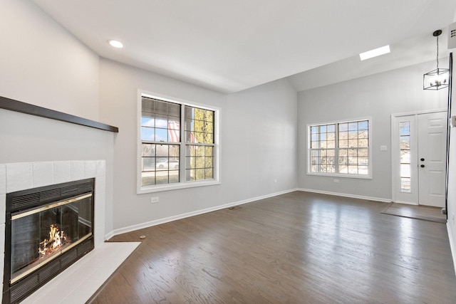 unfurnished living room featuring a notable chandelier, dark wood-type flooring, and a tiled fireplace