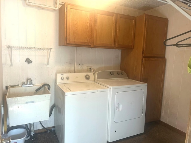 laundry area with cabinets, washing machine and clothes dryer, wood walls, and sink