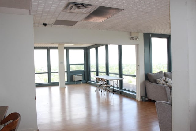 interior space featuring a wall of windows, wood-type flooring, and a wall unit AC