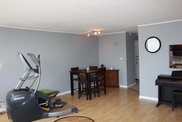 interior space with a textured ceiling, light wood-type flooring, and ornamental molding