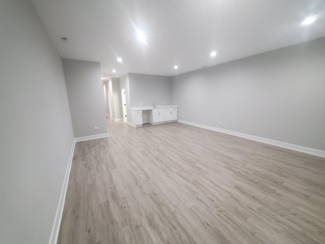 unfurnished living room with built in desk and light hardwood / wood-style flooring