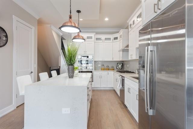 kitchen with a kitchen island, pendant lighting, light hardwood / wood-style flooring, appliances with stainless steel finishes, and white cabinets