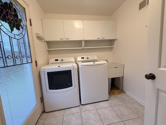 laundry area featuring separate washer and dryer, light tile patterned flooring, and cabinets