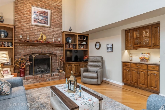 living room with light hardwood / wood-style floors and a brick fireplace