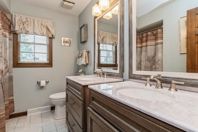 bathroom featuring tile patterned flooring, vanity, toilet, and a healthy amount of sunlight