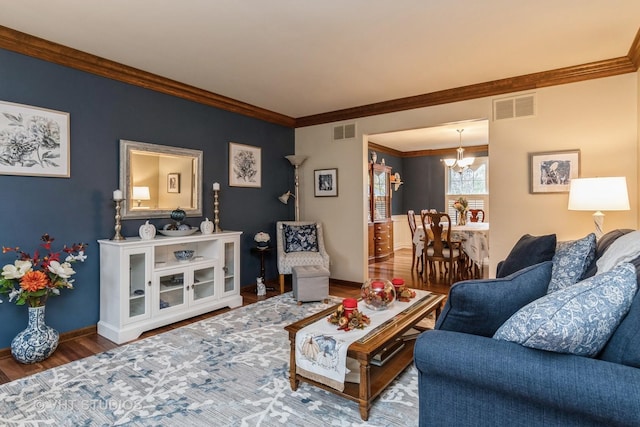 living room featuring wood-type flooring, an inviting chandelier, and crown molding