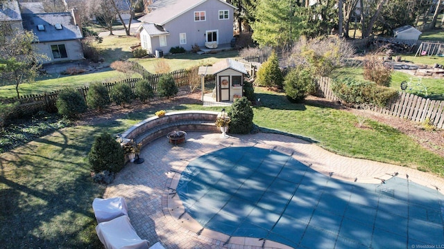 view of pool with a patio, a fire pit, a storage unit, and a lawn