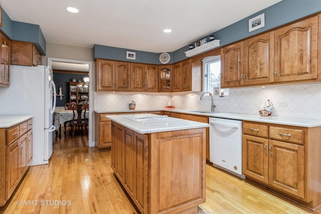 kitchen with decorative backsplash, white appliances, sink, light hardwood / wood-style floors, and a kitchen island