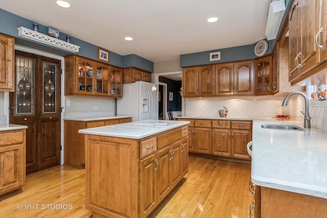 kitchen with sink, backsplash, light hardwood / wood-style floors, white appliances, and a kitchen island