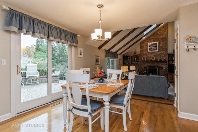 dining area featuring a fireplace, hardwood / wood-style floors, vaulted ceiling with beams, and an inviting chandelier