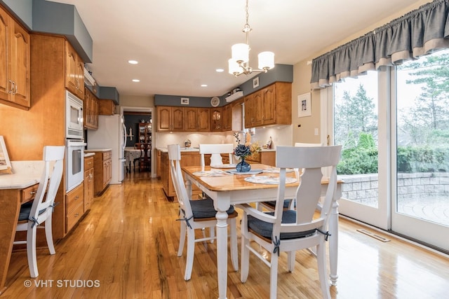 dining room with light hardwood / wood-style floors and an inviting chandelier