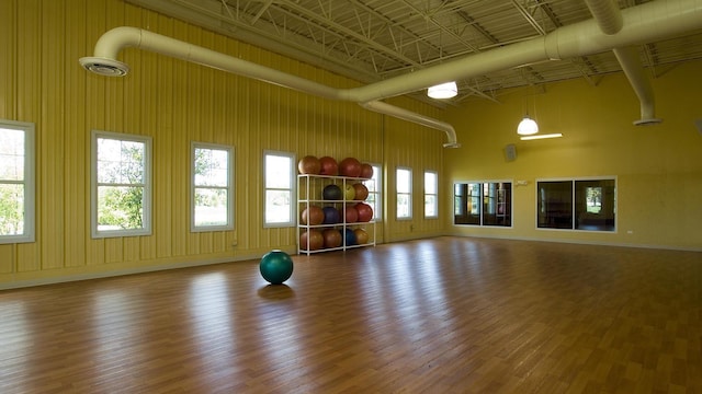 exercise room featuring a towering ceiling and hardwood / wood-style flooring