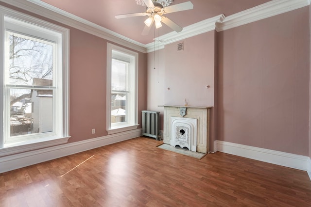 unfurnished living room featuring ceiling fan, ornamental molding, wood-type flooring, and radiator heating unit