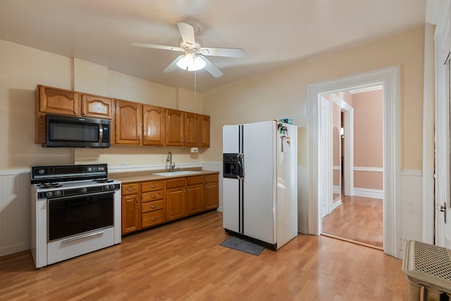 kitchen with light hardwood / wood-style flooring, ceiling fan, sink, white fridge with ice dispenser, and range with gas cooktop