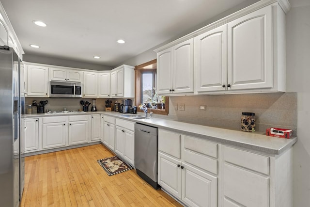 kitchen with backsplash, white cabinets, sink, light hardwood / wood-style flooring, and stainless steel appliances