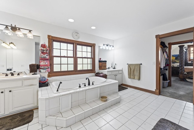 bathroom with tiled tub, tile patterned flooring, and vanity