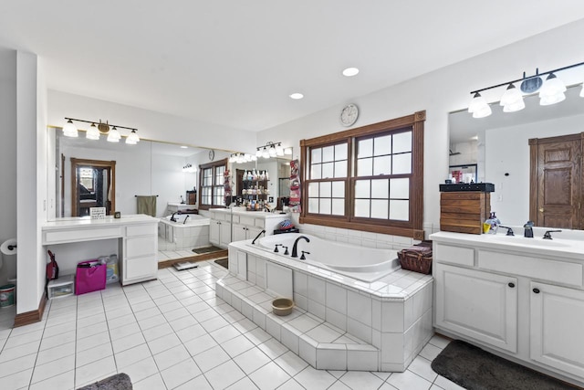 bathroom featuring tile patterned floors, vanity, and a relaxing tiled tub