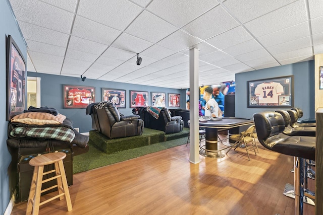 game room featuring a drop ceiling, golf simulator, and hardwood / wood-style flooring