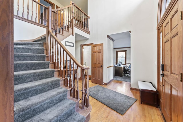 entrance foyer with hardwood / wood-style floors and a towering ceiling