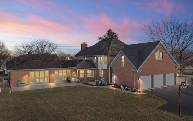 back house at dusk with a yard and a garage