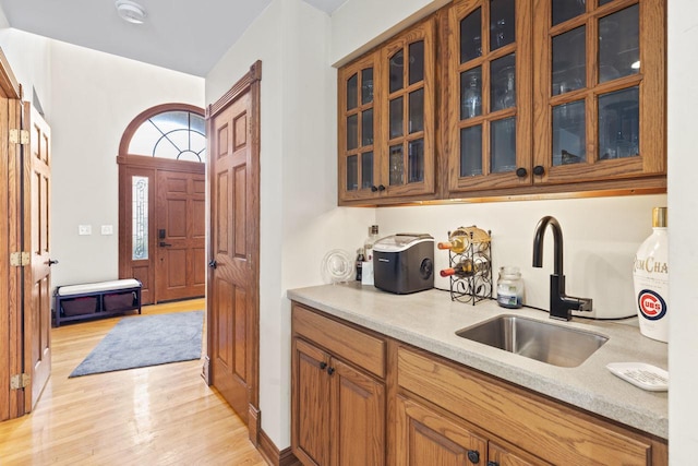 kitchen with light stone countertops, light wood-type flooring, and sink